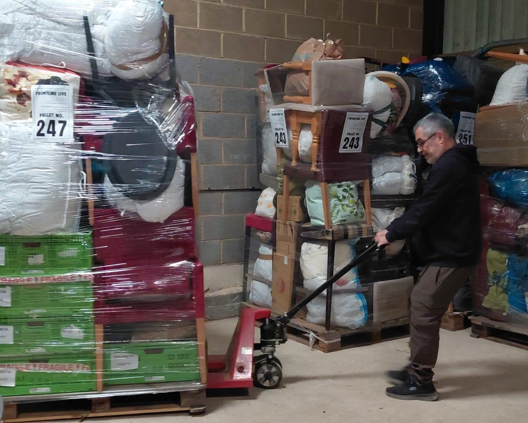 Tony moving pallets with aid supplies